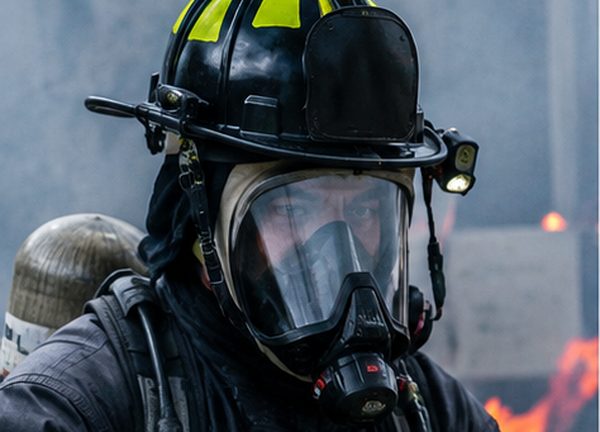 Bombero equipado con casco, máscara de respiración y protección certificada para emergencias